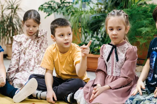 Дети беседуют, сидя на ковре
